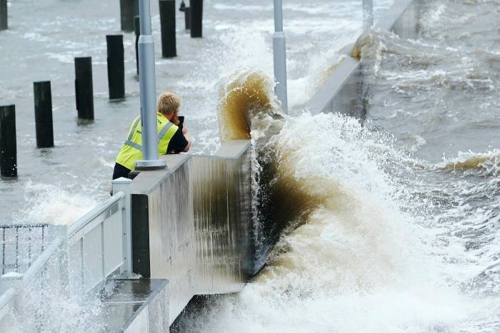 A utility worker photographs waves at a sea wall in Bay Saint Louis, Mississippi, as Hurricane Ida approaches