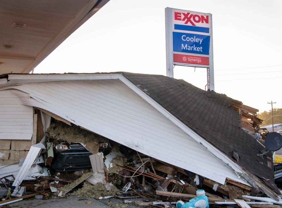 <p>A car peeks out from under a house that was destroyed by floodwaters at the Cooley Market in Waverly, Tennessee</p>