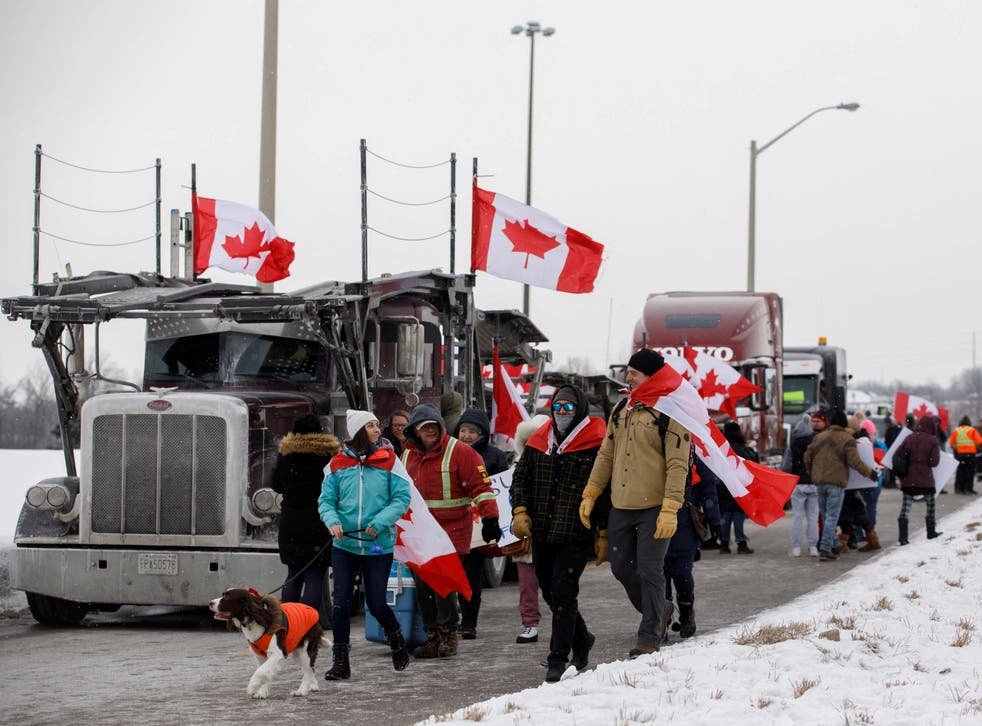 <p>Supporters of the ‘Freedom Convoy’ of truckers driving from British Columbia to Ottawa in protest against a Covid-19 vaccine mandate gather near a highway overpass outside of Toronto, Ontario</p>